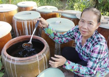 Bay Muon with her urns of fish sauce in Can Tho City, Vietnam. Photo: Chi Cong / Tuoi Tre